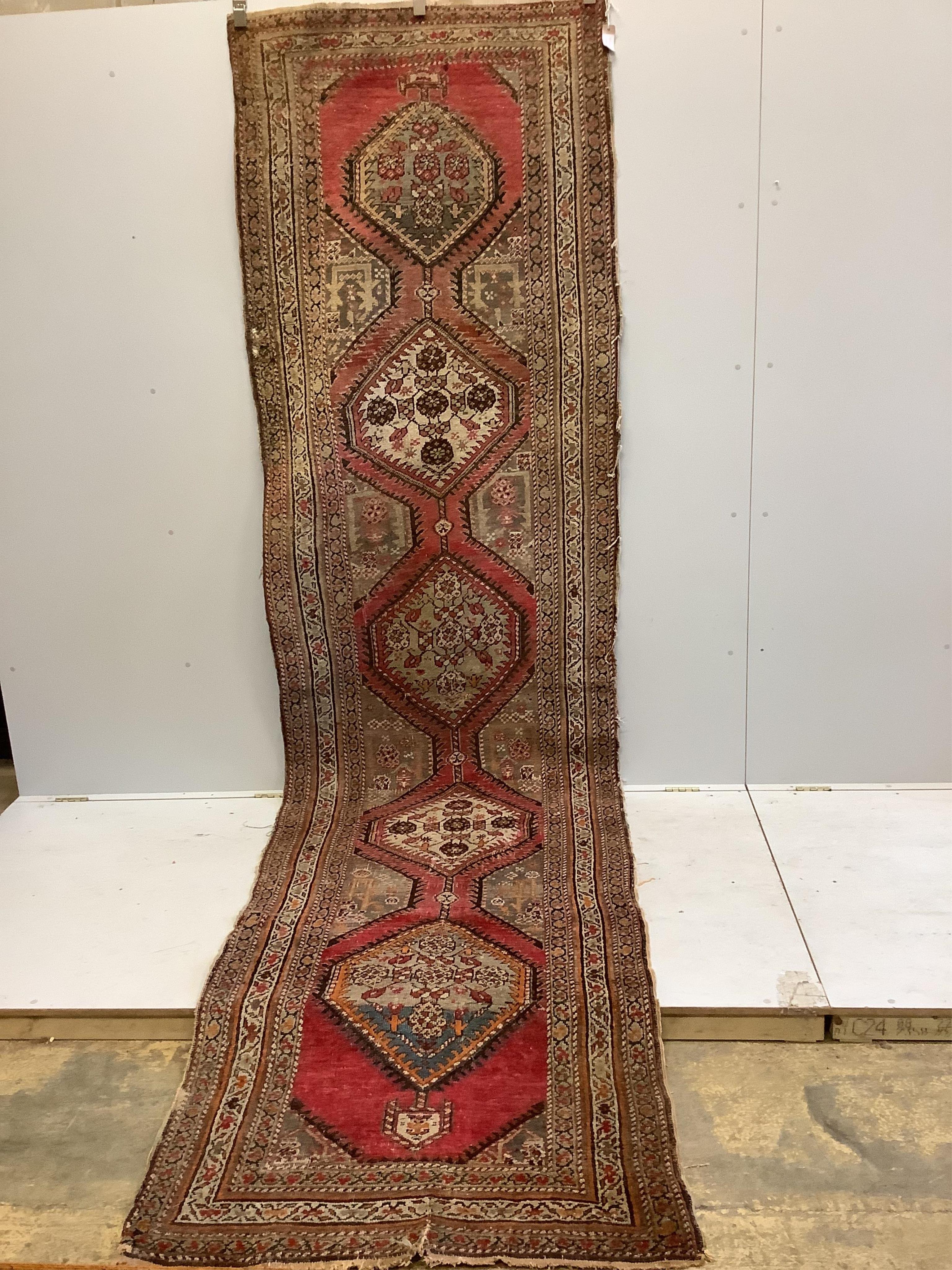 A Caucasian red ground runner, woven with a row of octagons, 416 x 106cm. Condition - fair